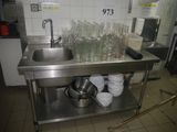 un évier en inox dans une cuisine où de la vaisselle est posée sur le plan de travail