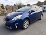 the blue toyota prius parked in a parking lot next to a pile of wood