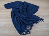 a blue scarf with fringes laying on a wooden floor