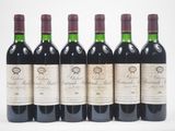six bouteilles de vin sont alignées sur une surface blanche