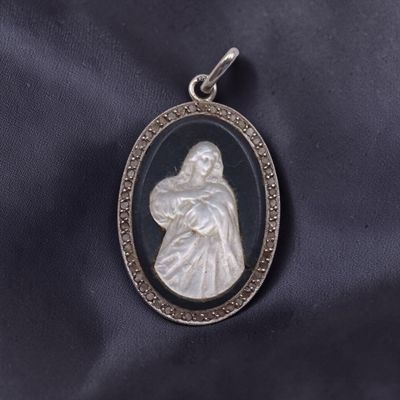 un pendentif en argent orné d'une image en noir et blanc représentant une femme tenant un enfant dans ses bras