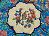 a colorful tile with a bird and flowers on it
