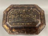 an old black and gold box sitting on top of a white surface