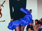 a woman that is walking down the runway wearing a blue skirt