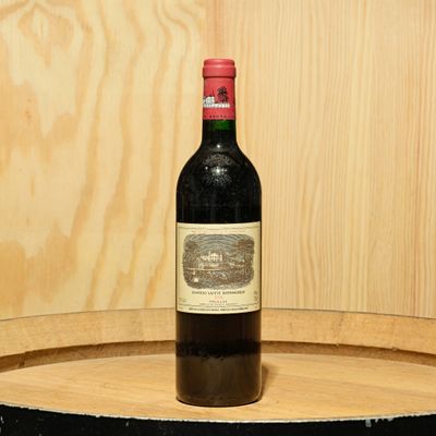 a bottle of wine sitting on top of a barrel