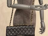 a mannequin holding a black purse on a mannequin stand