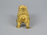 a gold figurine of a dog on a white surface