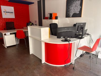 un comptoir d'accueil rouge et blanc sur lequel sont posés deux ordinateurs