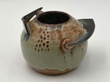 a small tea pot with a handle on a white surface