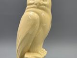 une figurine de chouette perchée sur un rocher, posée sur une surface grise