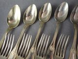 six spoons and six forks sitting on a table