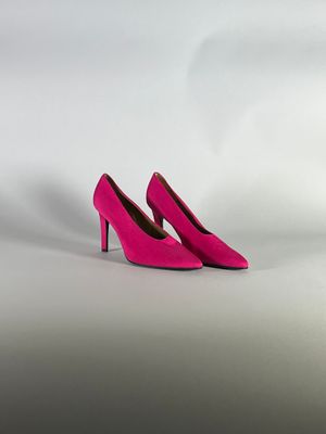 un gros plan sur une paire de chaussures à talons hauts roses posées sur une surface blanche