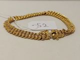 un bracelet en chaîne d'or muni d'un fermoir, posé sur un fond blanc