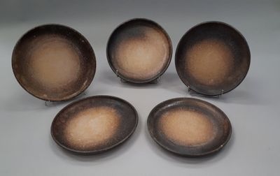 four brown plates sitting on top of a white table next to each other