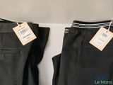 two pairs of black pants with tags on them hang on a wall