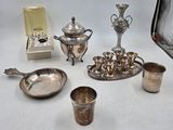 Plusieurs objets plaqués argent sont disposés sur une surface blanche