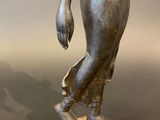bronze statue of a woman holding a flower in her right hand