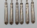 five silver spoons and a knife are lined up on a table