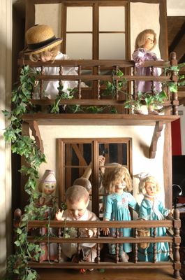 tout un tas de poupées qui se trouvent sur le balcon d'une maison de poupées