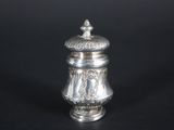 an antique silver salt shaker on a black background