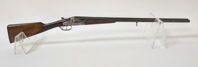 un fusil avec un canon en bois et un socle en plastique transparent