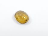 a yellow sapphire stone on a white surface