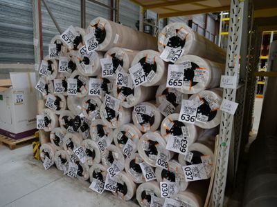 Plusieurs rouleaux de papier toilette sont empilés sur une palette dans un entrepôt