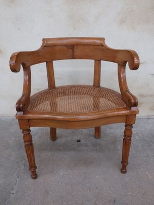 a wooden chair with a woven seat on a concrete floor
