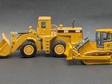 four toy construction vehicles sitting next to each other on a gray surface