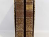 an old pair of books sitting next to each other on a white surface
