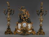 une horloge surmontée d'une statue, à côté de trois bougies
