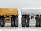 a yellow dump truck and a white dump truck side by side