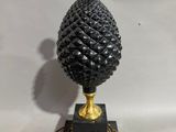 a black and gold table lamp with a pine cone on top