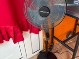 un ventilateur posé par terre devant une fenêtre