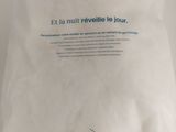 white pillow with blue writing on it sitting on a white surface