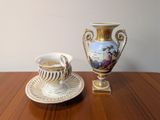 a cup and saucer sitting on a table next to a vase