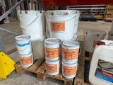 plusieurs seaux de peinture posés sur une palette dans un entrepôt