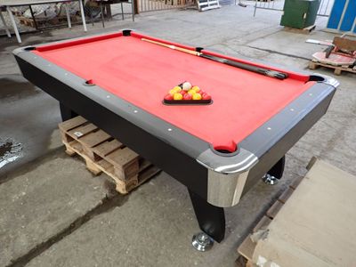 une table de billard avec des boules dessus, dans un entrepôt