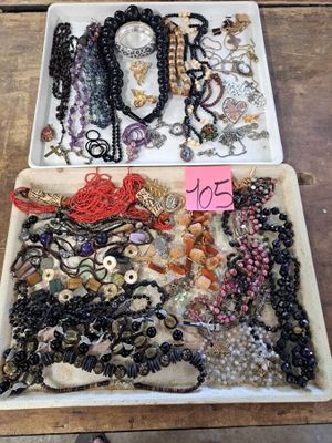 two trays filled with assorted jewelry on a wooden table