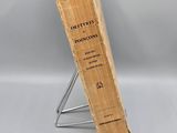 an old book sitting on top of a metal stand next to a white wall