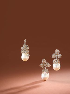 une paire de boucles d'oreilles en perles et diamants sur fond marron