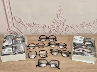 Plusieurs paires de lunettes sont posées sur une table devant un mur.