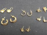 a bunch of gold earrings and earrings on a black surface
