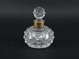 un flacon de parfum en verre transparent avec un bouchon doré, sur fond noir