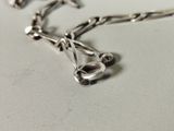 a silver necklace with a chain attached to it on a table
