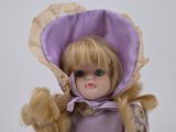 a doll that is wearing a purple hat and dress