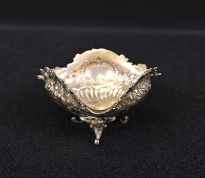 an antique silver plate with a shell in the center on a black surface
