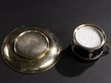 a silver cup and saucer on a black table