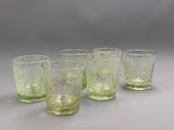 quatre verres verts posés sur une table blanche