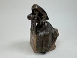 une statue en bronze d'une femme assise sur un rocher